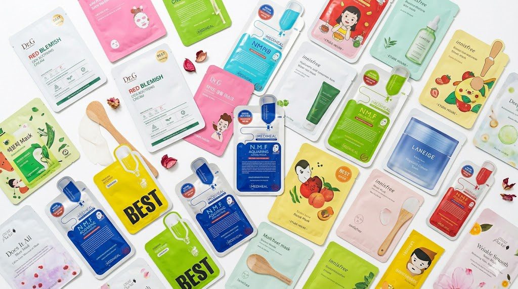 Various Korean sheet mask packets spread on a clean white surface