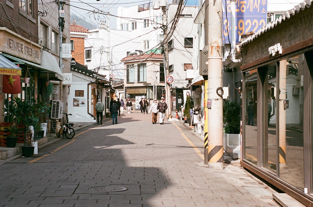 People walk down a narrow street lined with shops.