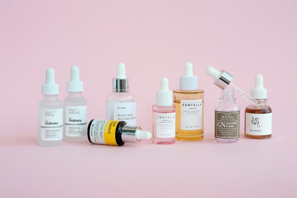 Skincare products are arranged on a pink background.