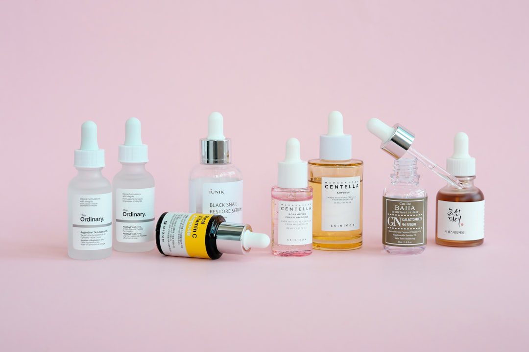 Skincare products are arranged on a pink background.