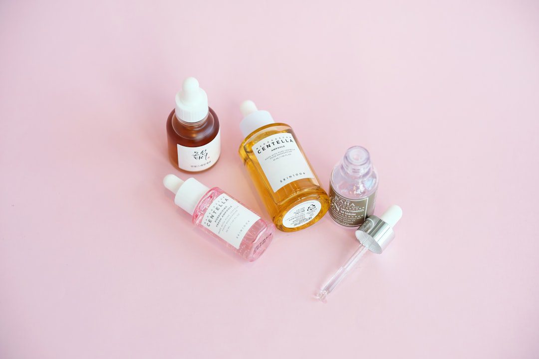 Skincare serum bottles arranged on a pink surface.