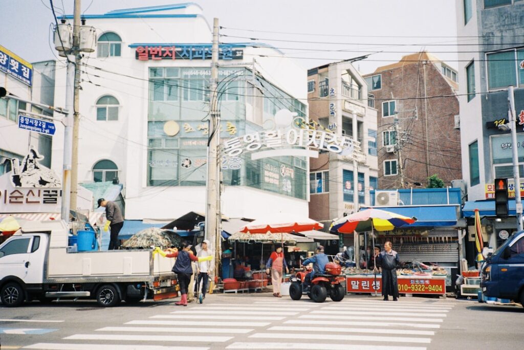 Street market scene with people and vehicles.