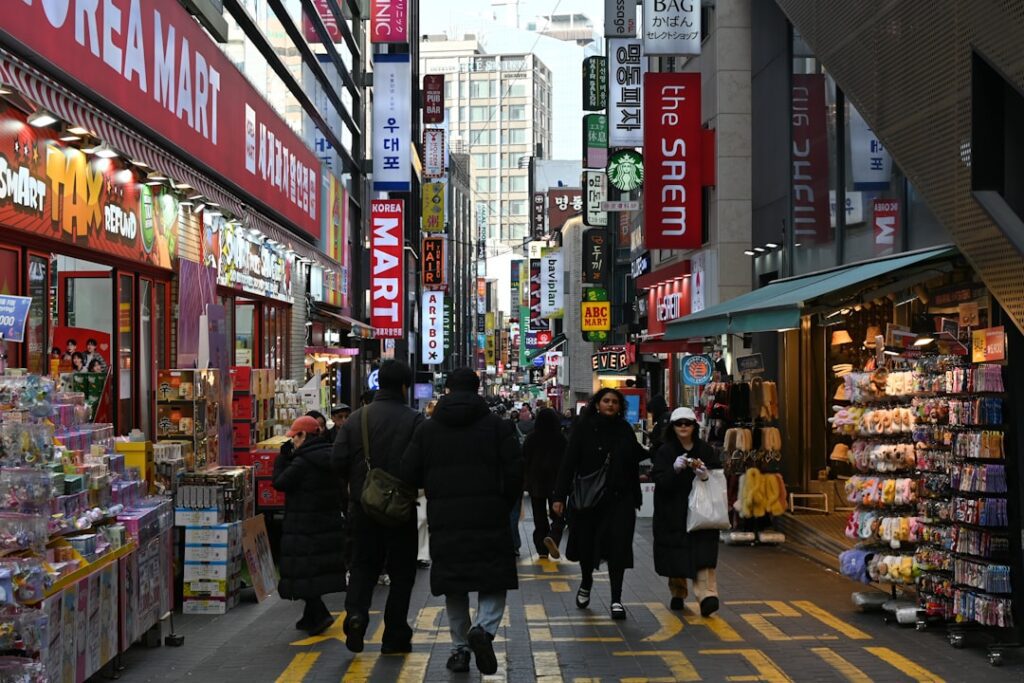 People walk down a busy street lined with shops.